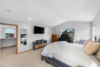 Spacious primary bedroom is filled with natural light and vaulted ceilings.