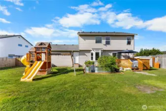 Large back yard comes with play set and garden that produces fruits and vegetables in containers.