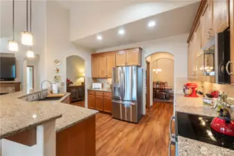 The kitchen features warm cabinetry with under lighting, Silestone countertops, tile backsplash and the stainless fridge with ice and water is included
