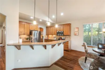 The kitchen offers a breakfast bar and casual dining space with view of the tranquil trees