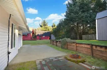 Step outside to a private setting featuring a greenhouse and a massive anchored shed on a gravel pad with a roll-up door, loft storage, and vehicle-ready access.