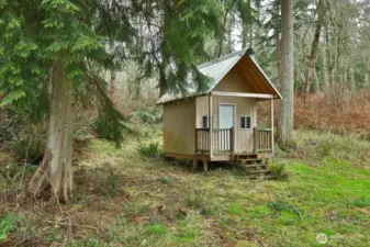 There is a small cabin within site of the patio located in the woods behind the house.  The interior is finished.