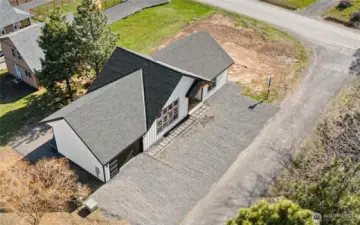 Aerial view highlights the home’s corner-lot setting, modern architecture, and surrounding natural landscape.