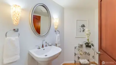 Half bath offers a wall hanging sink and hardwood floors.