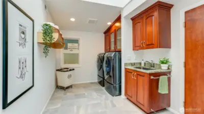 Spacious laundry room with tile flooring, cabinets, a deep sink and washer and dryer remain. This room connects the main 2 car garage to the rest of the home.
