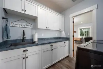 Spacious laundry room with great cabinet space, deep sink, washer/dryer included.  Laundry room looking towards living room.
