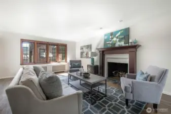 This spacious living room boasts rich hardwoods, gas fireplace with custom mantle and lead-glass windows.