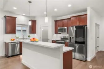 Stylish kitchen with rich wood cabinetry, quartz countertops, stainless steel appliances, and a convenient breakfast bar for casual dining.