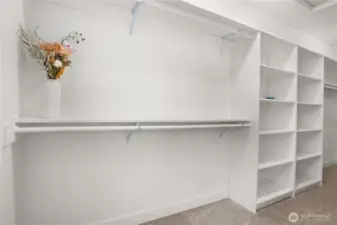 Expansive walk-in closet in the primary bedroom with built-in shelving and double hanging rods for optimal storage and organization.