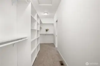 Large walk-in closet in the primary bedroom with extensive shelving, double hanging rods, and ample space for storage and organization.