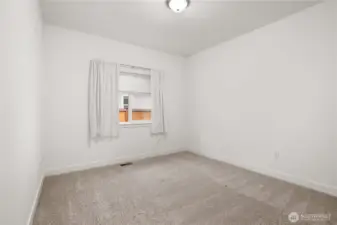 Comfortable secondary bedroom with plush carpeting and a bright window for natural light.