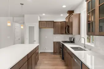 Kitchen features quartz counters and maple cabinets that are stained in graphite and full backsplash.