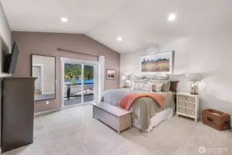 Main level primary bedroom with vaulted ceilings and view of Big Lake, private deck access through sliding doors to deck