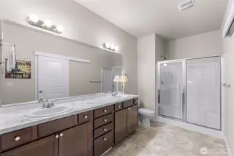 Large primary bathroom with enclosed standing shower, dual vanity and full length mirros, plenty of storage and large walk in closet