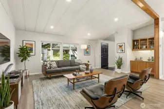 Formal living room with vaulted ceilings and new LVP flooring, opens to the family room and kitchen - Virtually staged photo