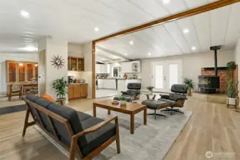 Formal living room with vaulted ceilings and new LVP flooring, opens to the family room and kitchen - Virtually staged photo