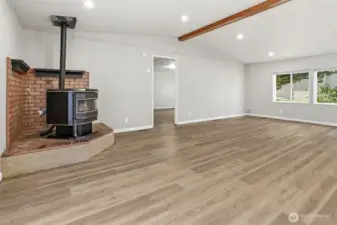 Family room with vaulted ceilings and new LVP flooring, french doors to the private back patio and courtyard, opens to the living room and kitchen