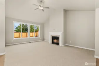 Living room with plenty of natural light featuring cozy gas fireplace with tile surround and ceiling fan.