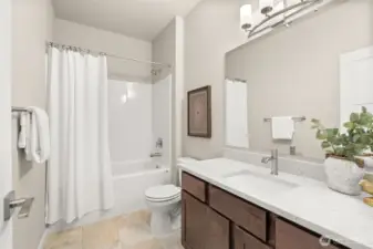 Full bathroom with undermount sink in Sable-stained Maple cabinet, quartz countertop with backsplash and tub/shower.
