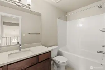 Crisp and clean 3rd bathroom located in second level with quartz countertop, maple wood cabinetry in sable-stain, and a shower tub combo.