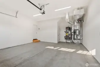 Spacious 2 car garage with extra storage. This photo also showcases HVAC system, water heater and clean concreate flooring.