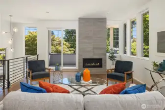 Great room with walkout covered deck, windows framing the space, and fire place (fire added for looks, buyer to verify functionality).