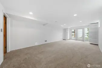 Large family room with carpet and French doors leading to patio.