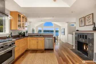 Kitchen with hardwood floors, fireplace, and beautiful water views connecting seamlessly to the dining space.