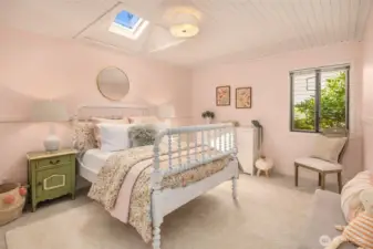 In the opposite wing from the primary is this light-filled bedroom with skylight, soft tones, and a warm, comfortable atmosphere.