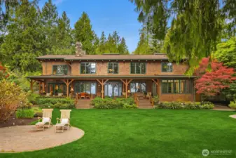 View of the back side (water side) of the main house with an expansive covered porch to enjoy and a nice flat lawn.