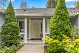 Walk up to this porch surrounded by established landscaping