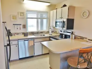 Fully-equipped Kitchen w/ Stainless Steel appliances, Eating Bar, and kitchenware.