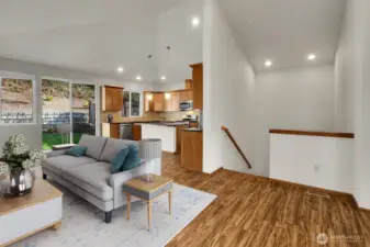 The open floor plan with vaulted ceilings creates a spacious atmosphere in the main living area on the upper level. Virtually staged.