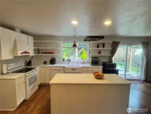 This home's open concept living flows from the kitchen with its easy to clean glass top range, plenty of cabinets and counter tops, including an island, to the family room. Just to the right is the sliding glass door that opens to the covered patio. The family room also has a wood burning fireplace. The floor is Luxury Vinyl Planking.
