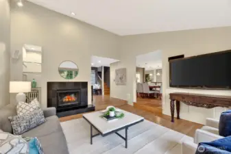 Open living space with fireplace, hardwood floors & seamless flow to dining area. Bright, inviting layout with modern touches & cozy ambiance.