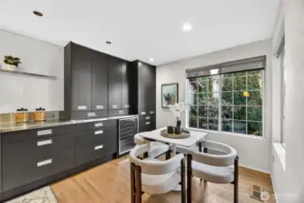 Bright eat-in kitchen with sleek cabinetry, stainless steel accents & wine fridge. Large window fills space with natural light, creating a stylish, cozy breakfast nook.