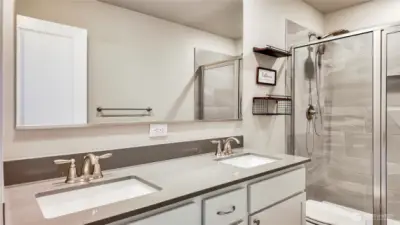 Primary bathroom featuring dual vanity and tiled shower with glass enclosure.