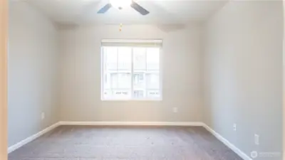 Bright secondary bedroom with ceiling fan and generous natural light.