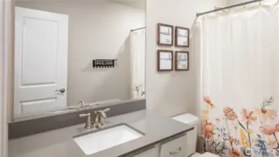 Hallway bathroom with single vanity and tub shower combination.