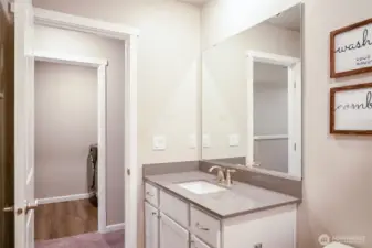 Spacious vanity with solid surface countertop and large mirror.