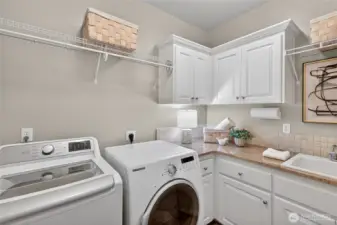 Main level laundry with utility sink and storage.