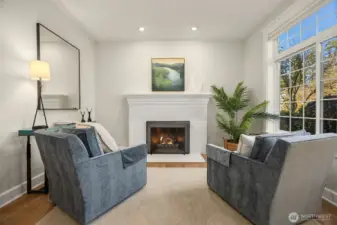 Painted brick, wood burning firepace with art wall and tall windows, a serene reading room.