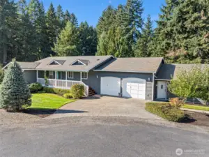 Front elevation of home with fully covered front porch and established apple trees.