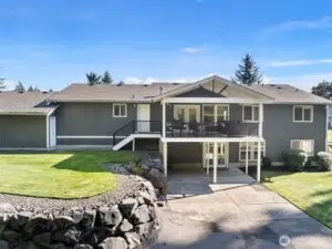 Rear elevation of home with paved back patio and upper fully covered Trex deck.