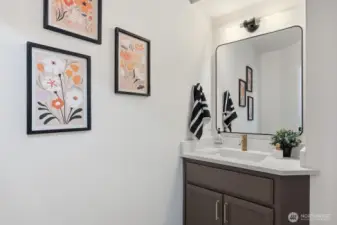 Thoughtfully updated main-floor half bath featuring tile,  quartz, undermount sink, mirror, lighting, faucet and hardware.