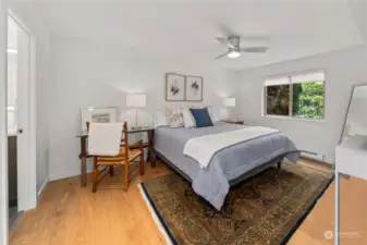 Generous primary bedroom continues with a light and bright pallet with a ceiling fan to keep the air circulated.