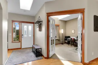 Sunny entry with hardwood floors and skylight. View into the den.