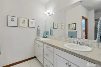 Primary bathroom with 2 sinks, walk in shower and a toilet closet. Tile floors.