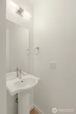 A chic powder room that gets the job done—stylish lighting, a modern pedestal sink, and perfect for guests popping by.