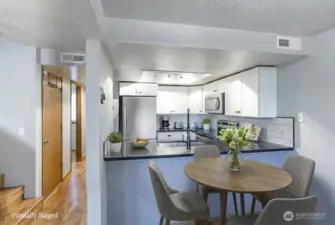 This photo captures another excellent perspective of the dining area seamlessly connected to the inviting open kitchen. A particular highlight is the charming breakfast bar, providing a perfect spot for relaxed, casual meals and everyday gatherings.